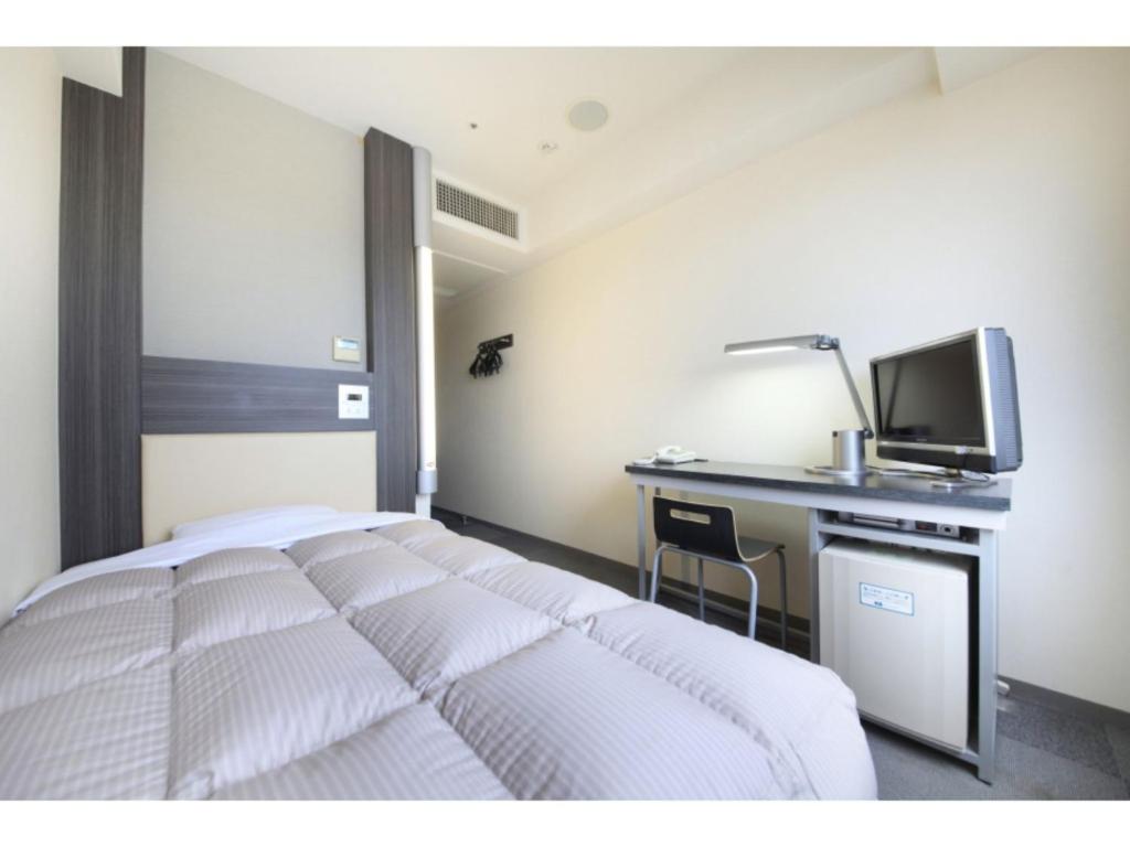 um quarto com uma cama, uma secretária e uma televisão em R&B HOTEL HACHIOJI - Vacation STAY 38830v em Hachioji