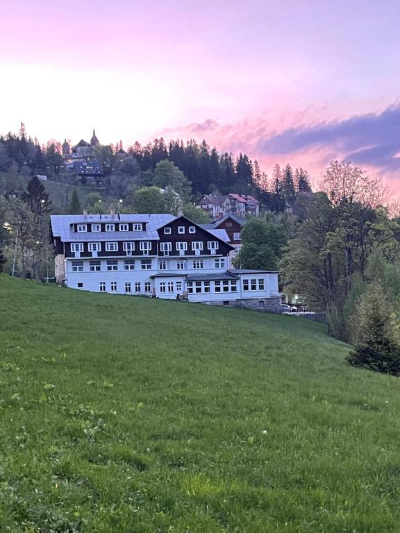 un grand bâtiment blanc au-dessus d'un champ verdoyant dans l'établissement Pod Gołębiem, à Karpacz