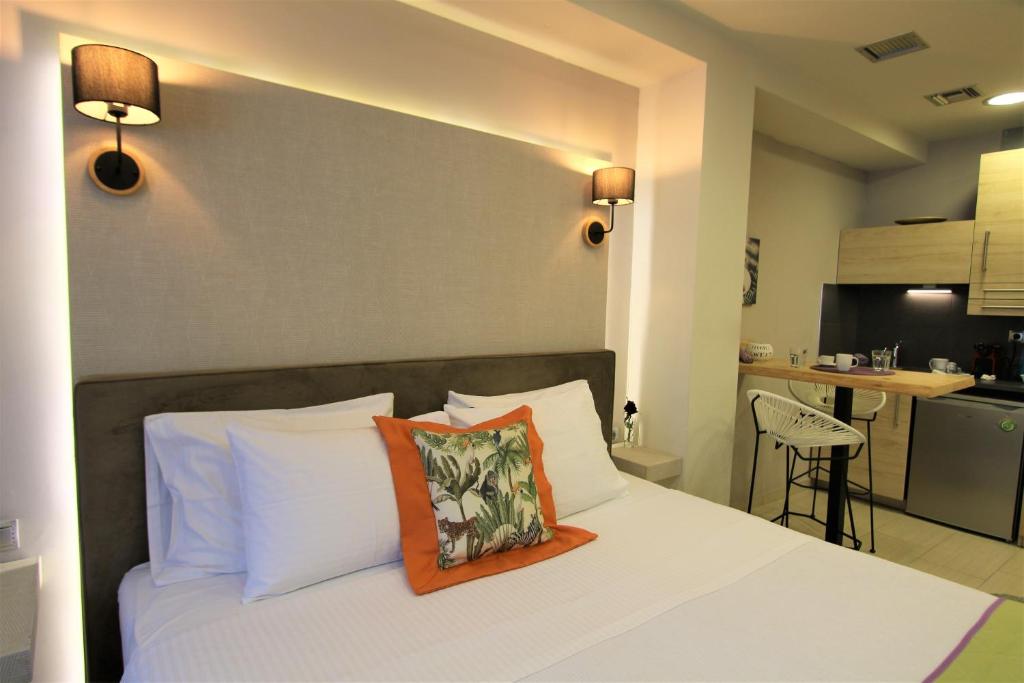 a bedroom with a white bed with an orange pillow on it at Aiolos Apartments Ermou 64 2nd Floor suites in Athens
