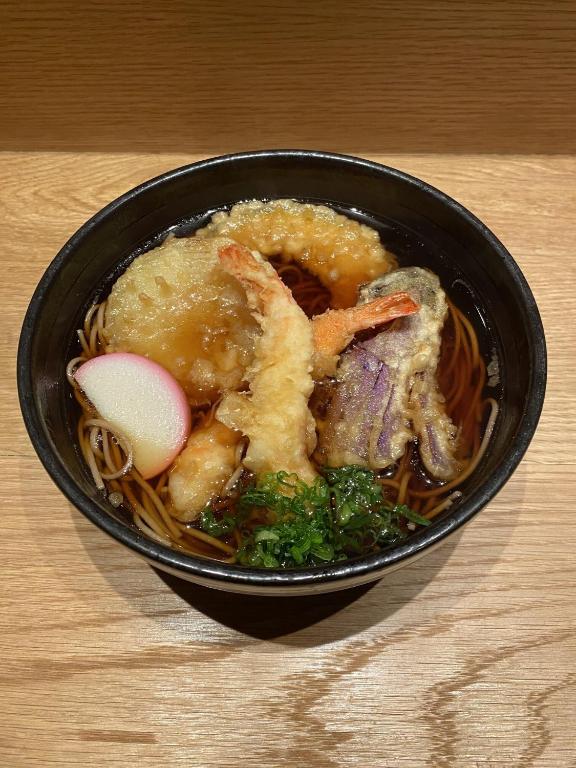 a black bowl of food with shrimp and noodles at Henn na Hotel New York in New York