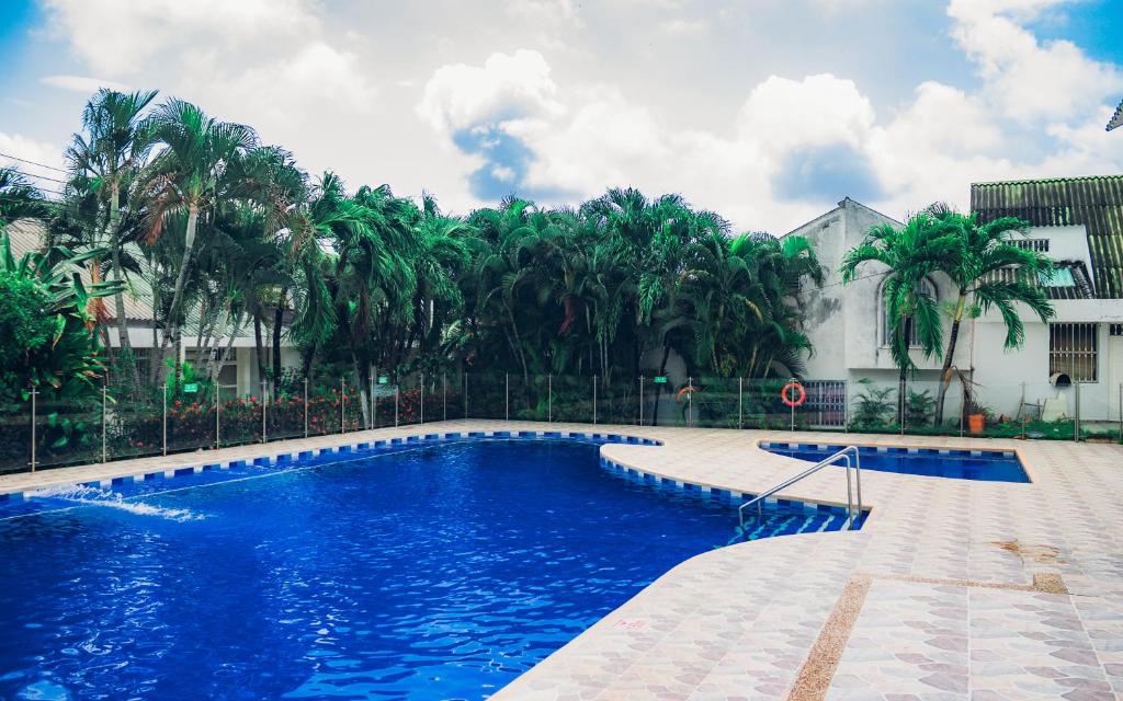 a swimming pool in front of a building with palm trees at Casa de descanso con Jacuzzi privado - Girardot in Girardot