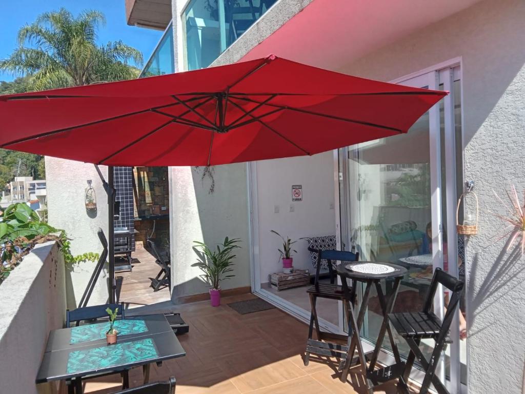 un ombrellone rosso su un patio con tavolo e sedie di Hospedagem Sol Nascente ad Atibaia