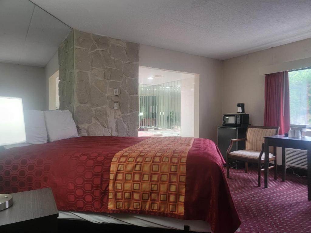 ein Hotelzimmer mit einem großen Bett mit einer Steinmauer in der Unterkunft La Mirage in Monmouth Junction