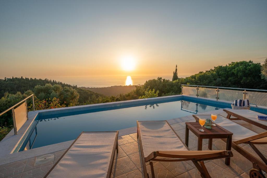 ein Pool mit einem Tisch und Stühlen und der Sonnenuntergang in der Unterkunft Stone Villa Eriphyle ,private witn sunset view in Fiskardo