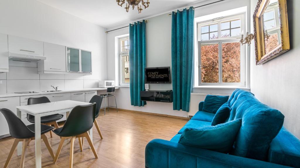 sala de estar con sofá azul y cocina en Comfy Apartments - Centrum Monte Cassino en Sopot