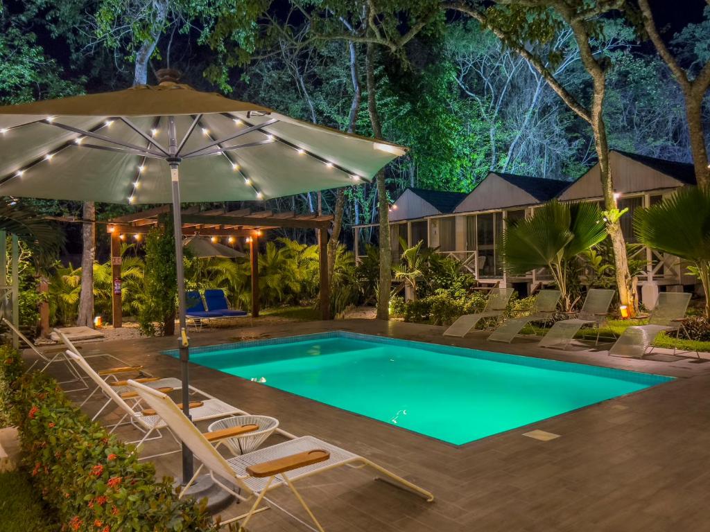 a pool at night with chairs and an umbrella at Zensus Eco Boutique Hotel in Bacalar