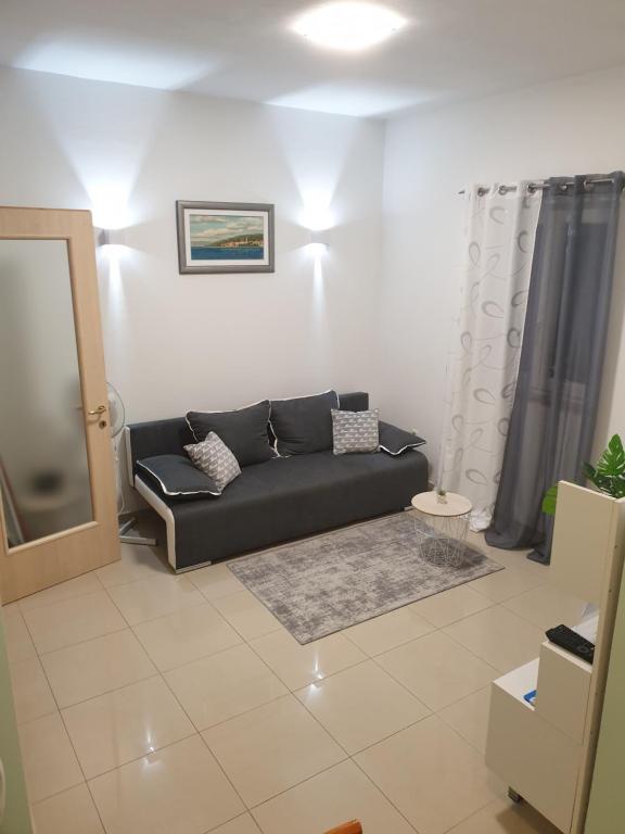 ein Wohnzimmer mit einem schwarzen Sofa und einem Spiegel in der Unterkunft Sophos in Supetar