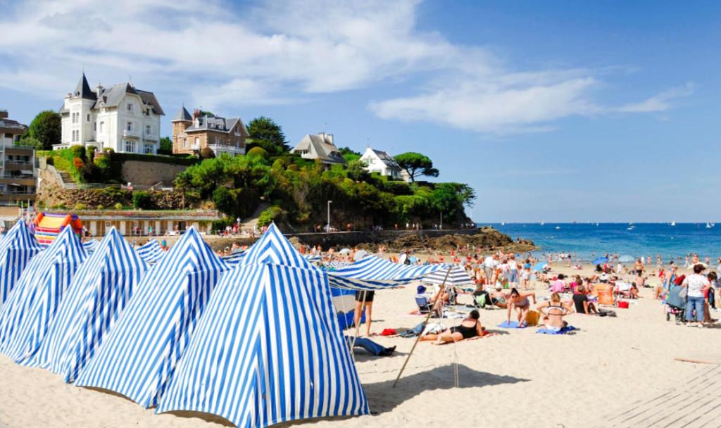 un groupe de parasols bleus et blancs sur une plage dans l'établissement JENNY'S HOME, à Pleurtuit