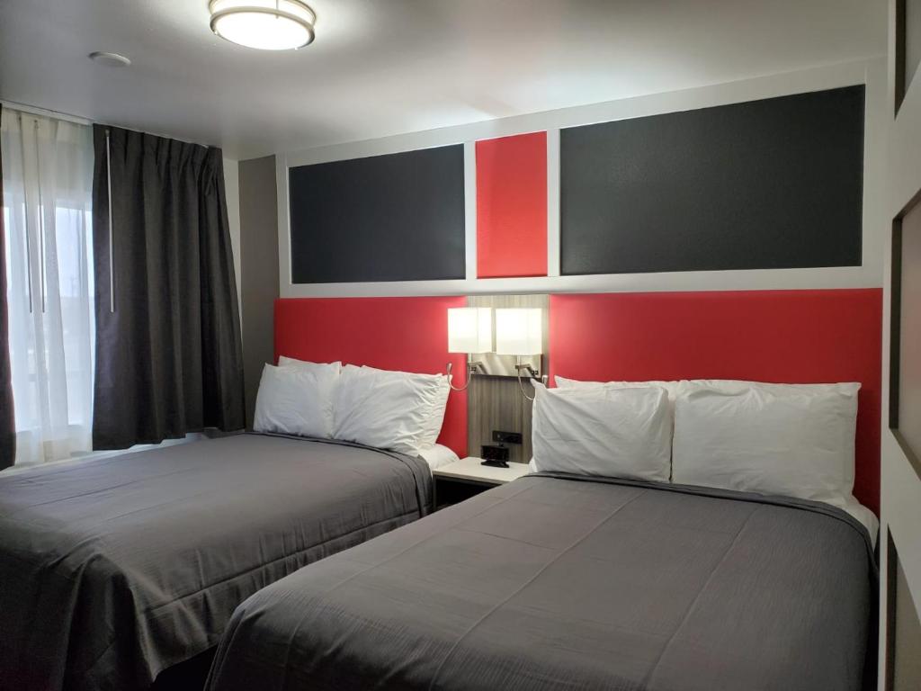 two beds in a hotel room with red walls at Money Saver Motel in Newport