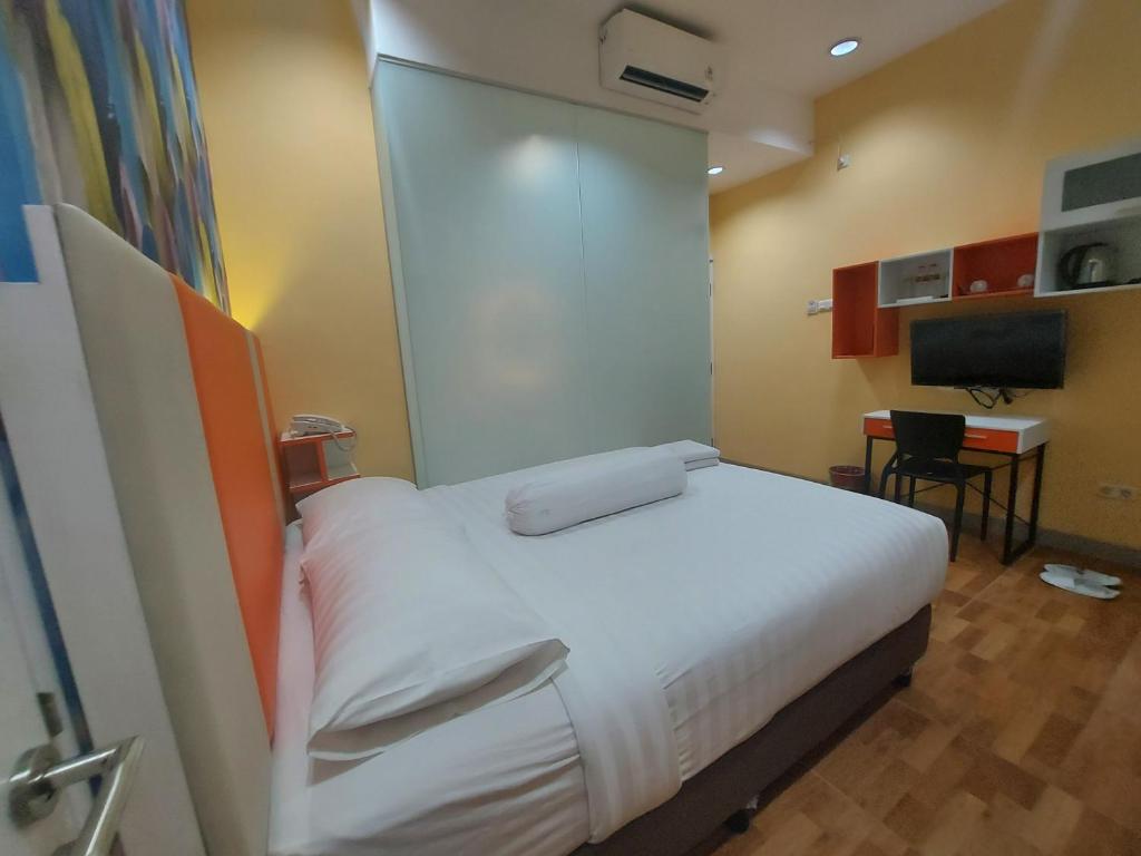 um quarto com uma cama, uma secretária e uma televisão em Rumah Familiku 1 Syariah em Wonocolo