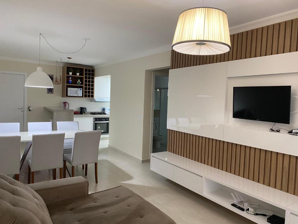 Apartamento Novo Praia de Bombas في بومبينهاس: غرفة معيشة ومطبخ مع تلفزيون وطاولة