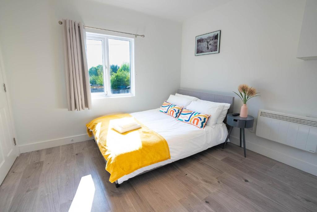 a bedroom with a bed with a yellow blanket and a window at No 02 Studio Flat Available near Aylesbury Town Station in Buckinghamshire