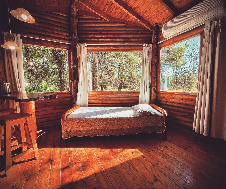 a bedroom with a bed in a cabin with windows at Posada del Viento in Tandil