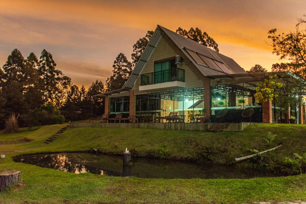 a house with a pond in front of it at Chakras Pousada in Jaguariaíva