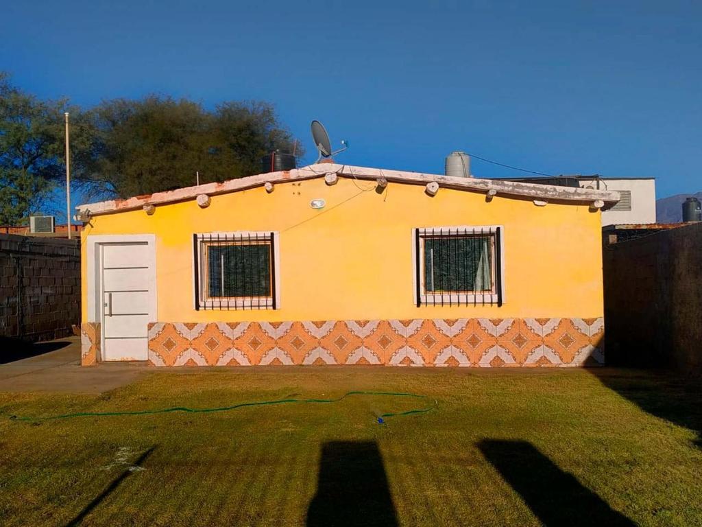 una casa amarilla con garaje en un patio en Casa Huguito en Tinogasta