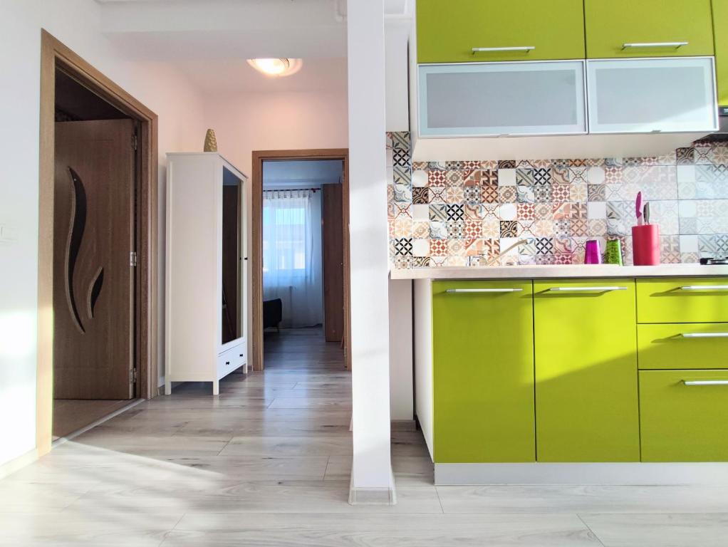 a kitchen with green cabinets and a hallway at Quiet and Cozy 2 bedroom flat with free parking included in Floreşti