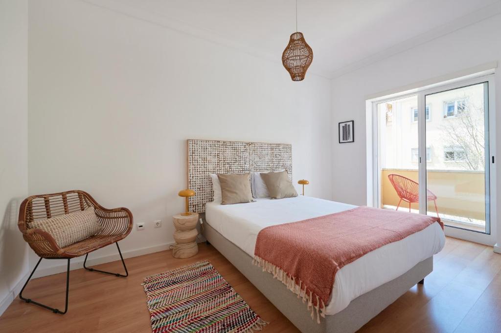 een slaapkamer met een bed, een stoel en een raam bij Sunset Balcony Apartment, By TimeCooler in Lissabon