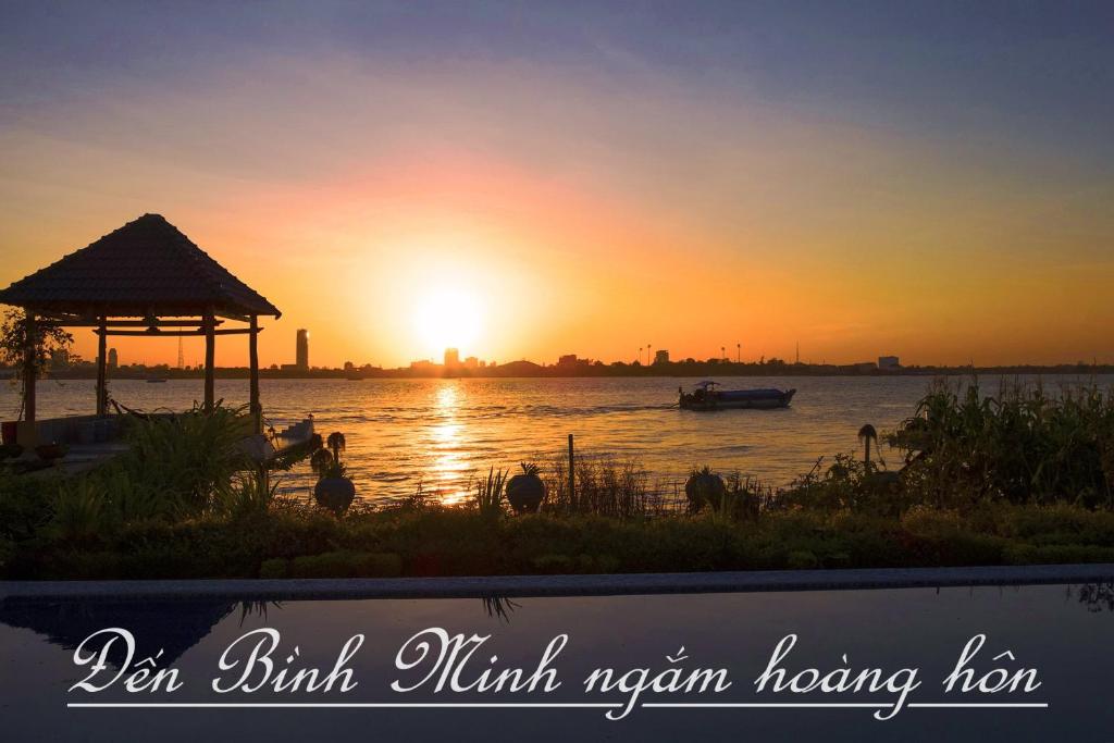 - un coucher de soleil sur une rivière avec un kiosque dans l'établissement Binh Minh Eco Lodge, à Cần Thơ