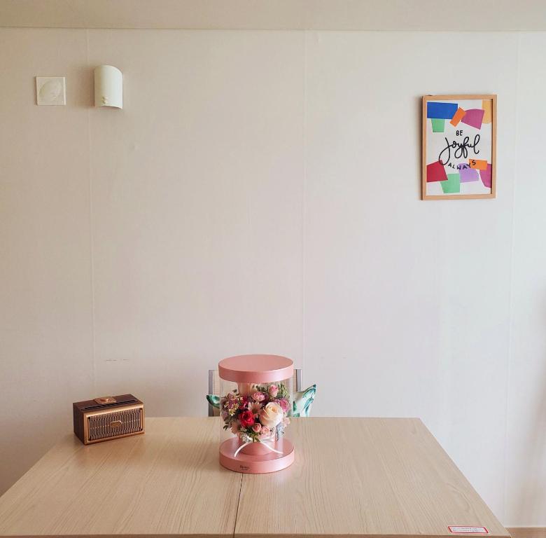 een roze vaas met bloemen op een houten tafel bij Cozy - Experience Home like Comfort Studio in Incheon