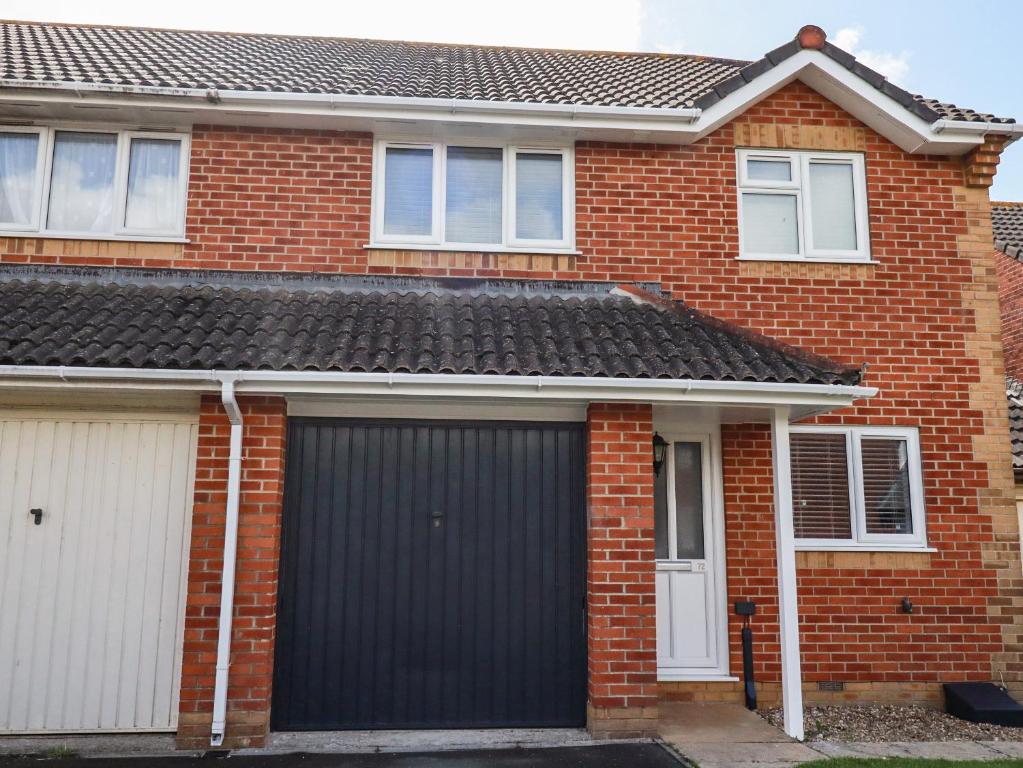 a black garage door on a red brick house at Sea Rest in Bude