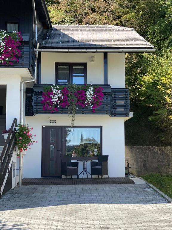 a white house with a table and a balcony with flowers at Apartma Vražič in Bled