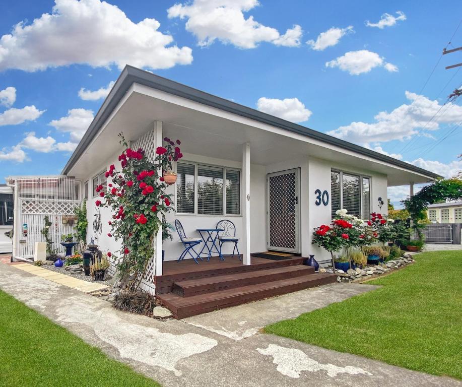 a white house with a deck with flowers on it at Rathlin Cottage in Twizel