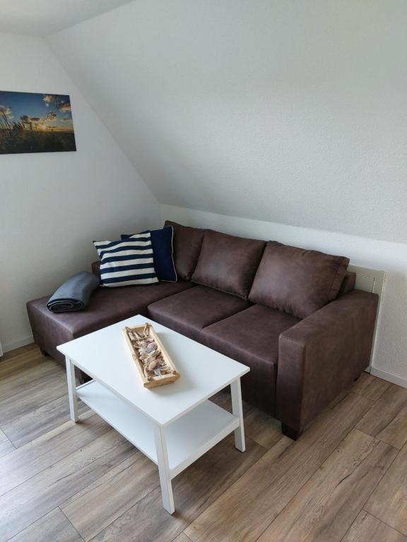 a living room with a brown couch and a white table at Backbord in Wangerland