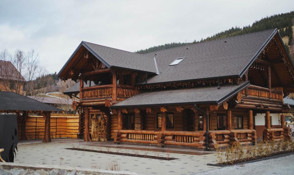 a large log cabin with a black roof at Hanul lui Mujdei in Vatra Dornei