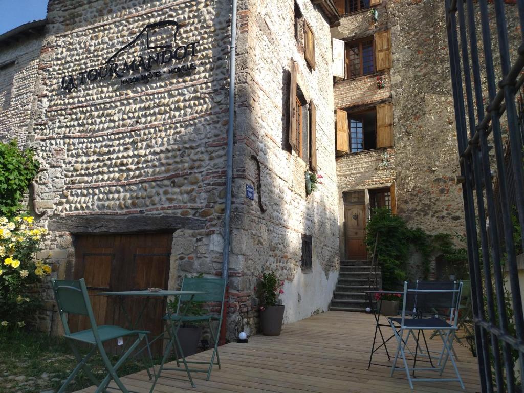 a brick building with chairs and a table on a deck at La Tour Mandot in Montluel