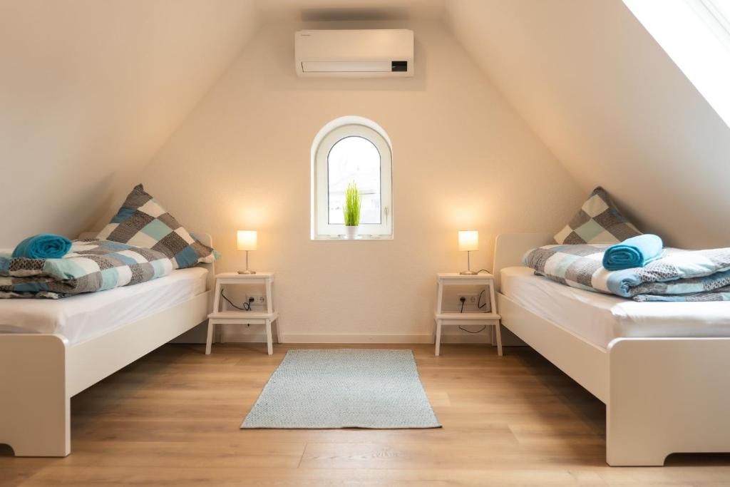 a attic bedroom with two beds and a window at Ferienwohnungen-Oberkochen.de Stadtherberge Sperberstraße in Oberkochen