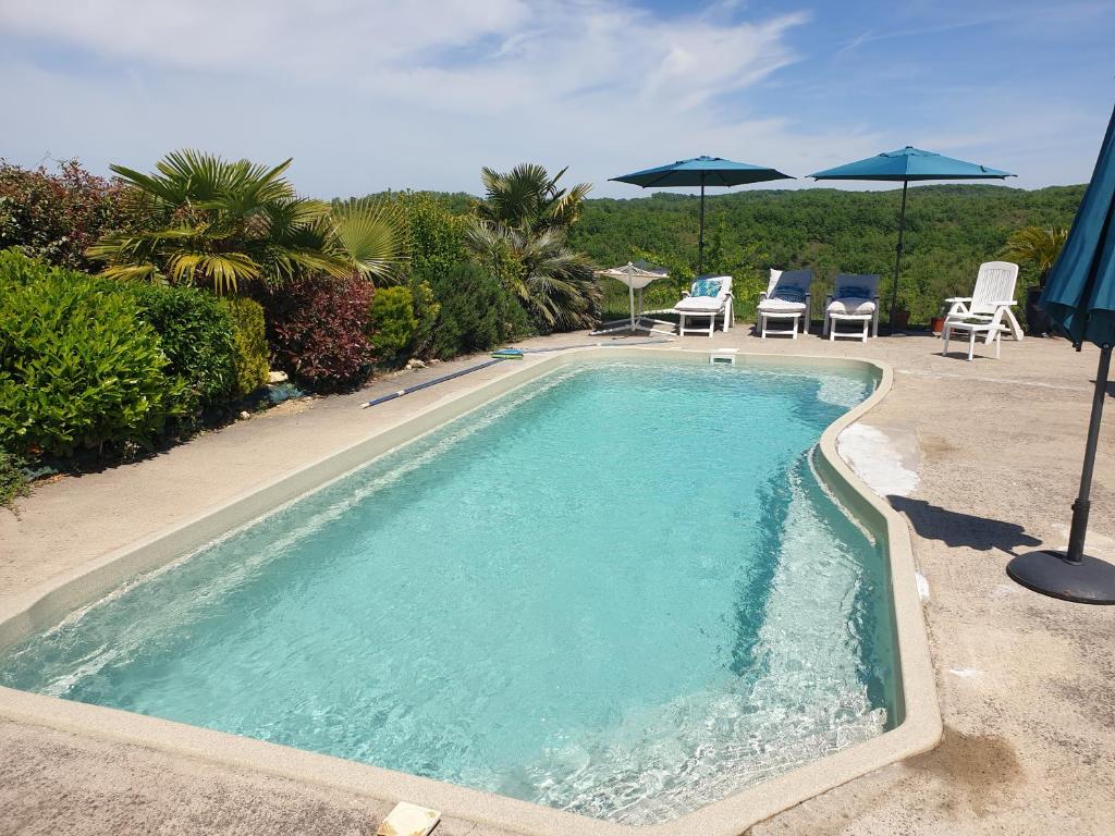 a swimming pool with chairs and umbrellas on a patio at Chambre d'hôtes à 10 mn au sud d'Auch in Orbessan