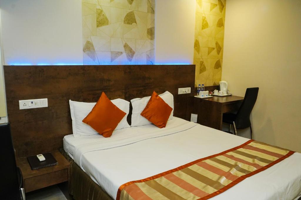 a bedroom with a bed with orange pillows and a desk at Hotel Spices Navi Mumbai in Ghansoli
