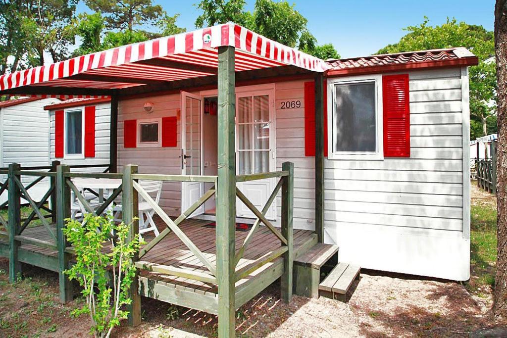 Cette petite maison rouge et blanche dispose d'une terrasse couverte. dans l'établissement Mobilehome in Caorle, à Caorle