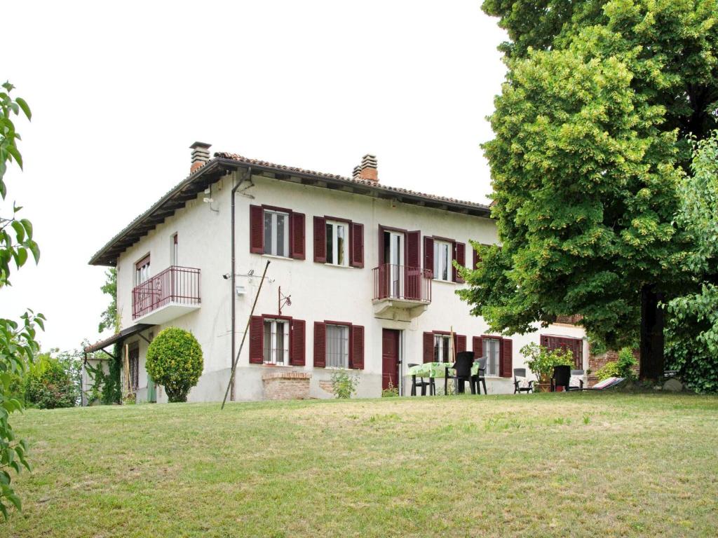 duży biały dom z czerwonymi oknami i drzewem w obiekcie Casa vacanze a Moncucco Torinese w mieście Moncucco Torinese