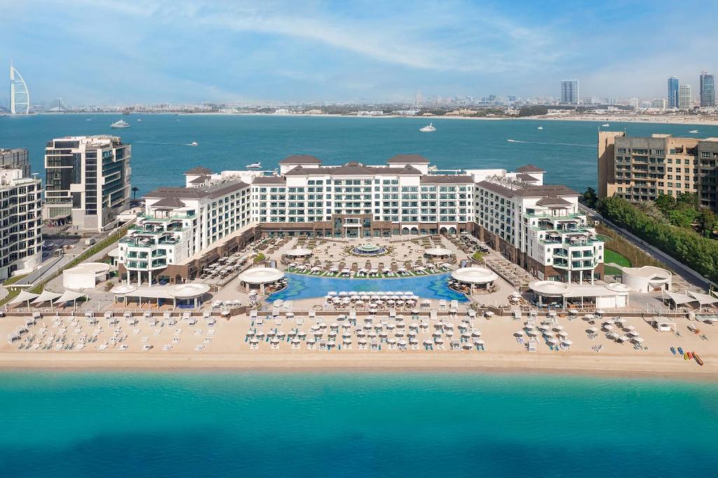 Taj Exotica Resort & Spa, The Palm, Dubai في دبي: اطلالة جوية على منتجع فيه كراسي ومظلات