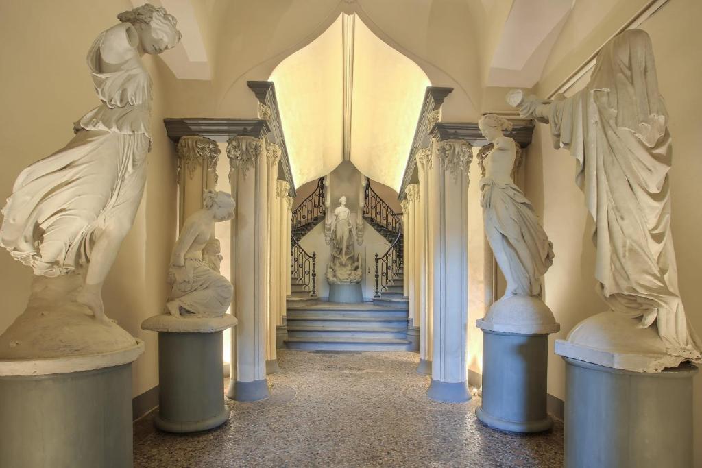 Luxury Suite in Florence - hosted by Sweetstay في فلورنسا: ممر به تماثيل نساء في المواقف