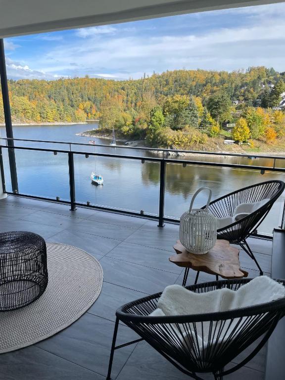 a balcony with a table and chairs and a view of the water at Apartments Saaldorf-Ferienhaus mit 6 Apartments 45qm-120qm direkt am Thüringer Meer-Bleilochtalsperre in Bad Lobenstein