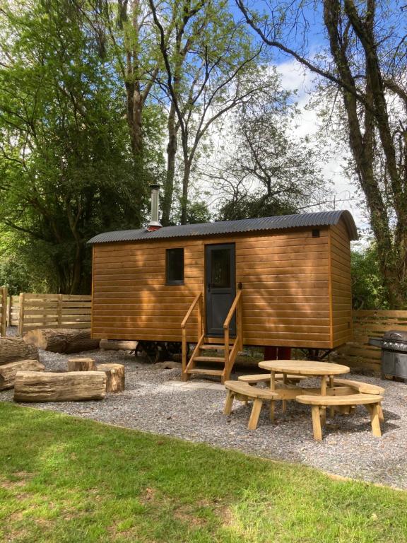 a wooden cabin with a picnic table and a bench at Herdwick Shepherd Hut in Exeter