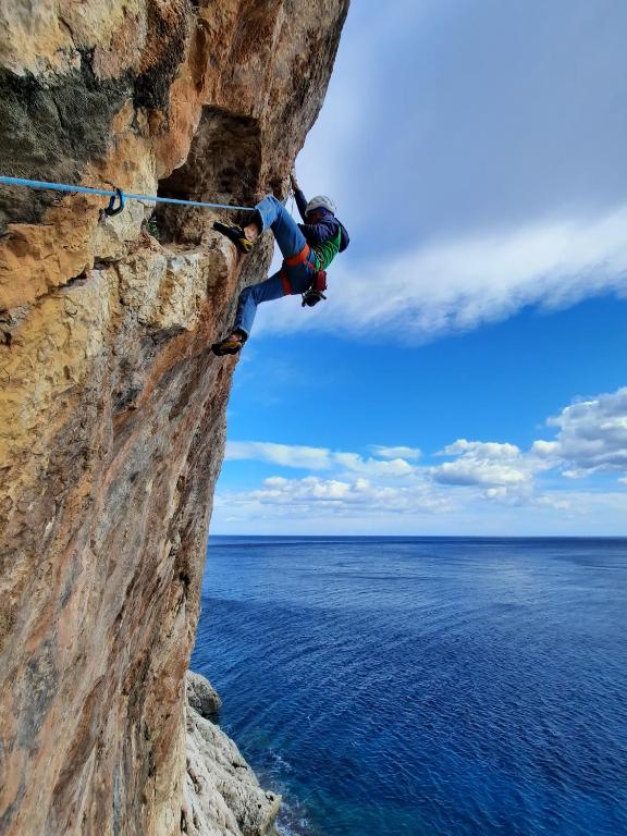 a person on a rock wall near the ocean at Biriola EcoResort Cala Gonone in Cala Gonone