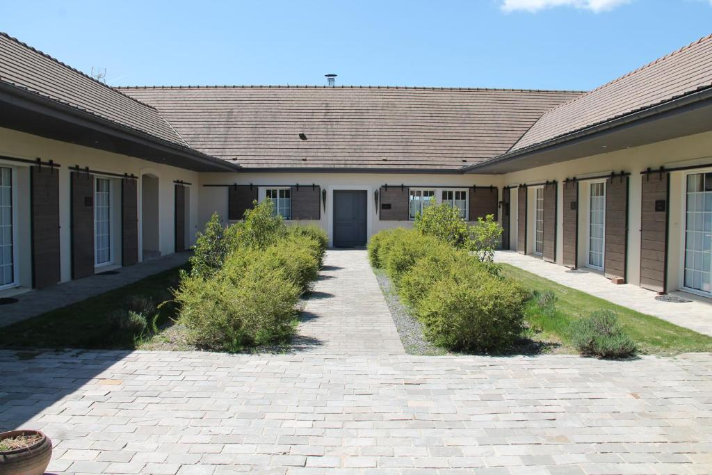 a building with a brick driveway and bushes at Le Clos 24 in Macherin