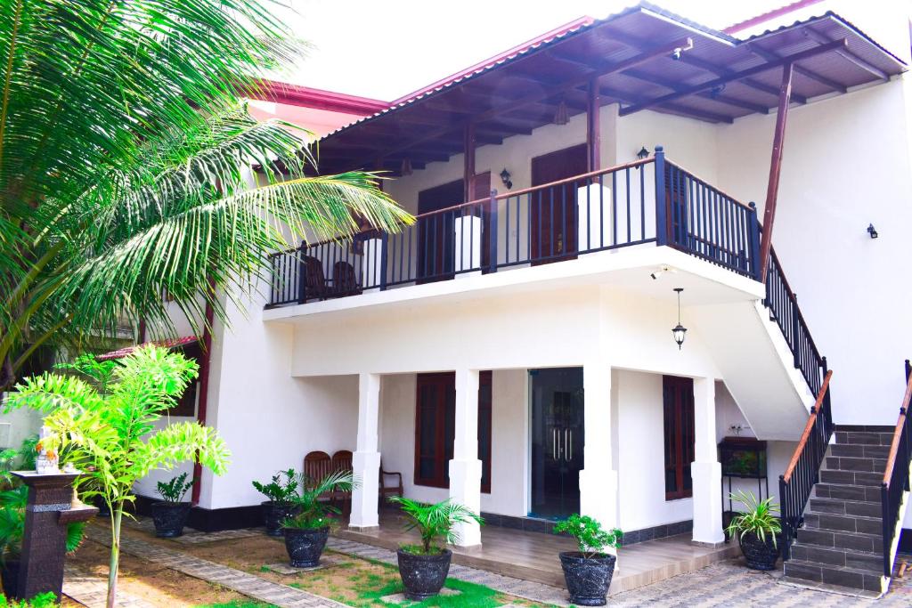 una casa bianca con balcone e alcune piante di Parallel villa a Trincomalee