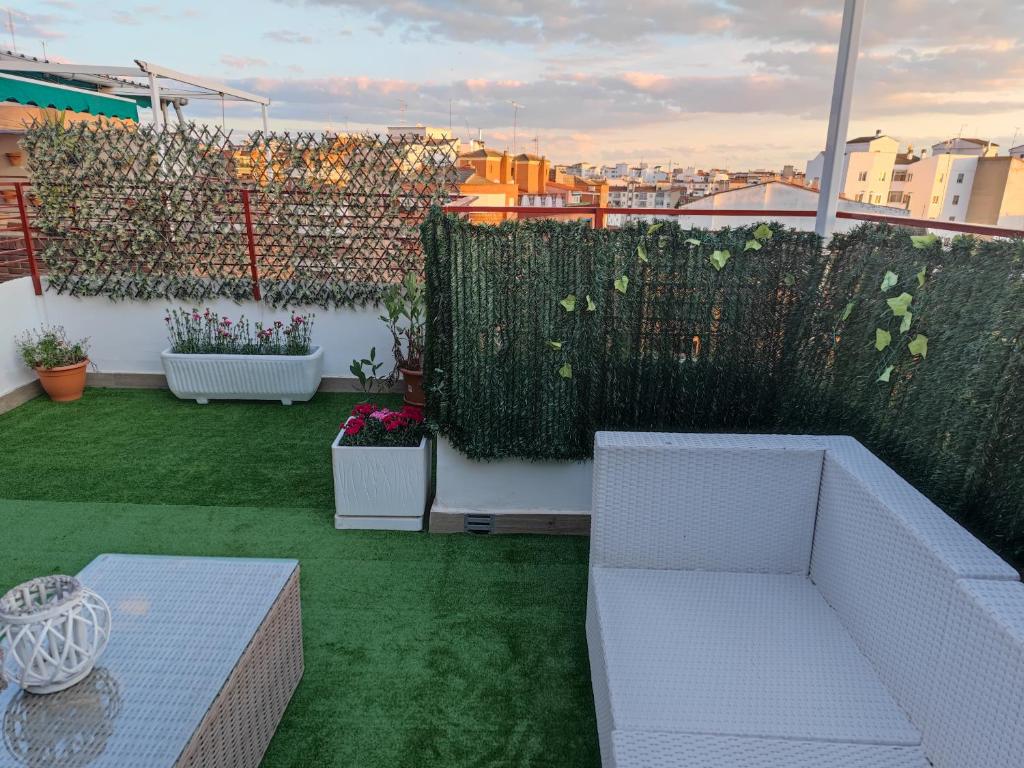 un toit-terrasse avec mobilier blanc et pelouse verte dans l'établissement Atico Gran Boulevard de Albacete - A 5 minutos de la Feria, à Albacete