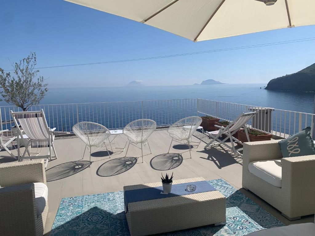 patio z krzesłami i stołami oraz widokiem na ocean w obiekcie 'A Alera Room & Breakfast w mieście Malfa