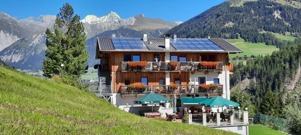 un edificio con paneles solares al lado de una colina en Braugasthof Glocknerblick en Kals am Großglockner