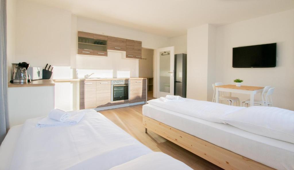 two beds in a room with a kitchen and a table at T&K Apartments - Studio Apartments - 22 min MESSE DUS & Airport DUS in Krefeld