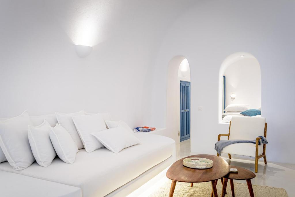 a white living room with a white couch and a table at Aristos Life Luxury Cave Villas in Oia