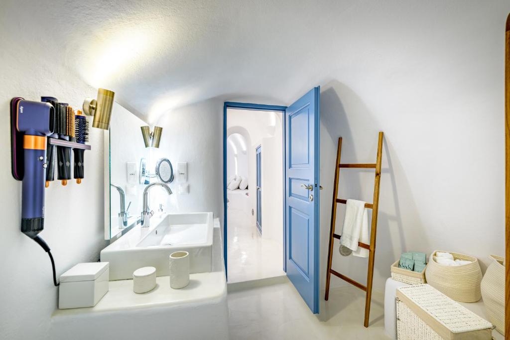 a bathroom with a blue door and a sink at Aristos Life Luxury Cave Villas in Oia