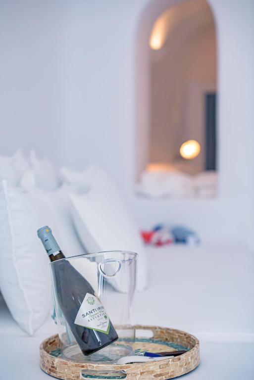 a bottle of wine on a table with a glass at Aristos Life Luxury Cave Villas in Oia