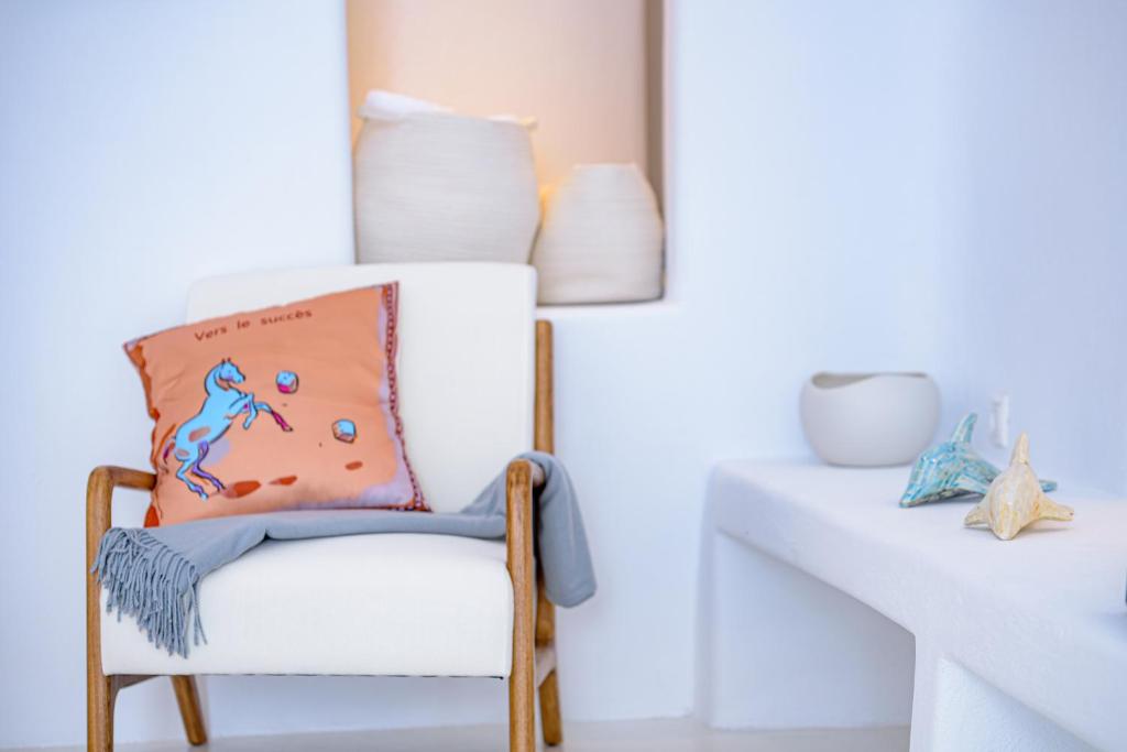 a white chair with a pillow on it next to a table at Aristos Life Luxury Cave Villas in Oia