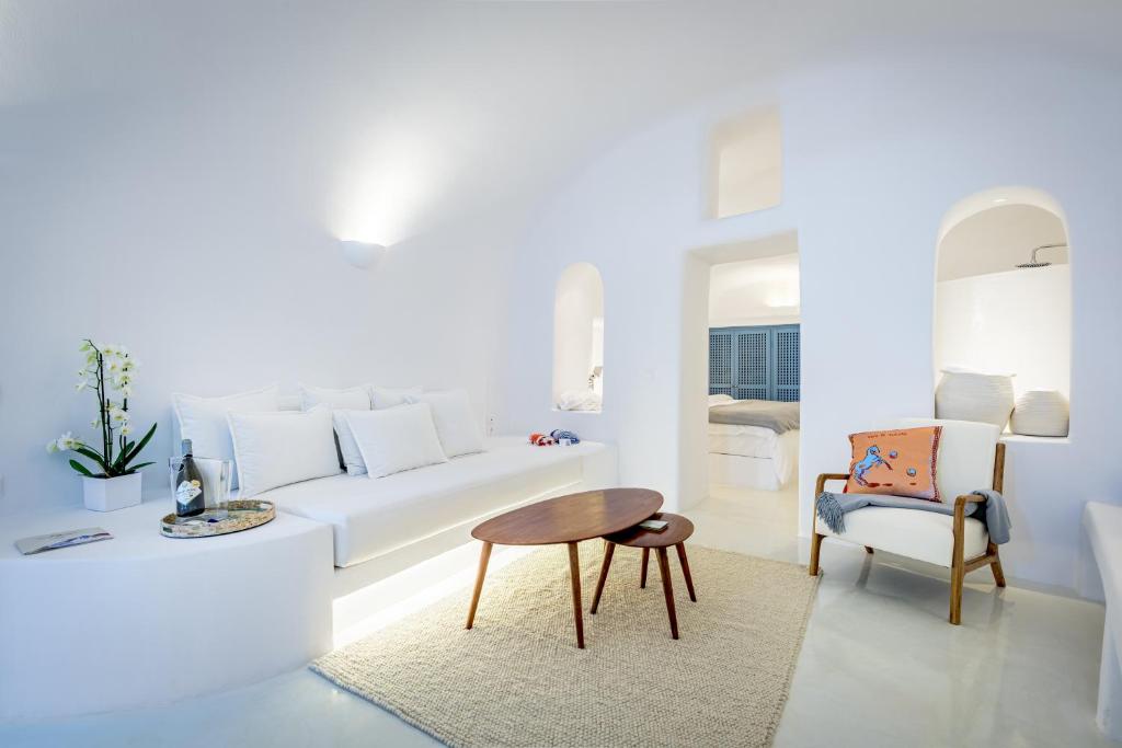 a white living room with a white couch and a table at Aristos Life Luxury Cave Villas in Oia